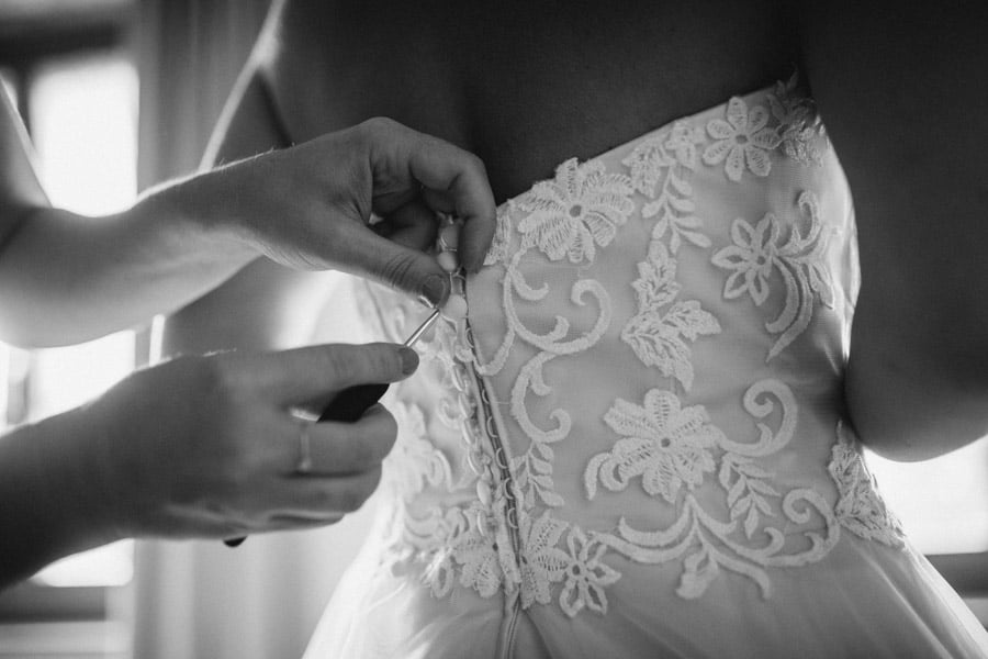 Trauzeugin knöpft Hochzeitskleid zu